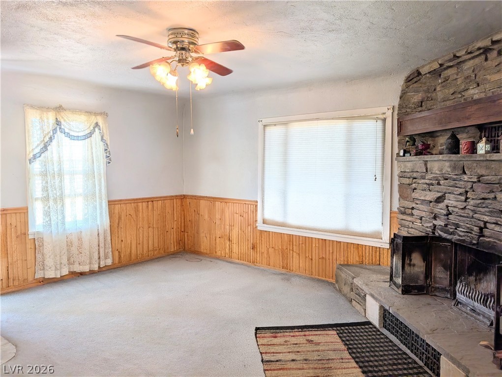 997 Phillips Street Panaca, NV 89042 - Photo 6 of 19 A comforting living room featuring a grand stone fireplace and warm wood paneling.