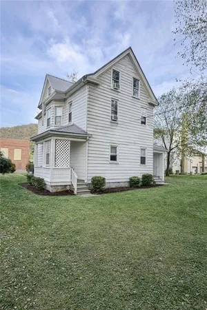 a view of a yard in front of a house with plants and large tree