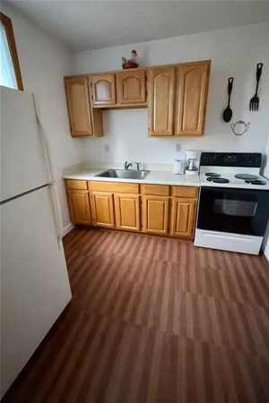 a kitchen with granite countertop wooden cabinets a stove and a sink