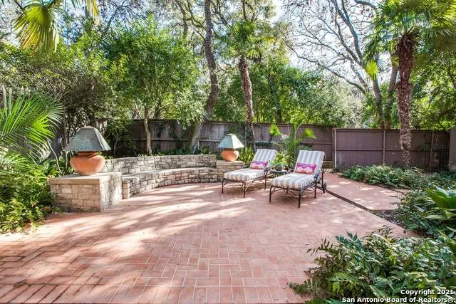 a view of a patio with table and chairs potted plants and large tree