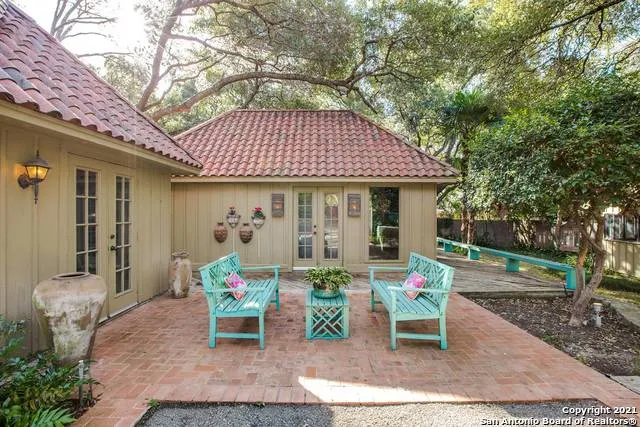 a patio with table and chairs and potted plants
