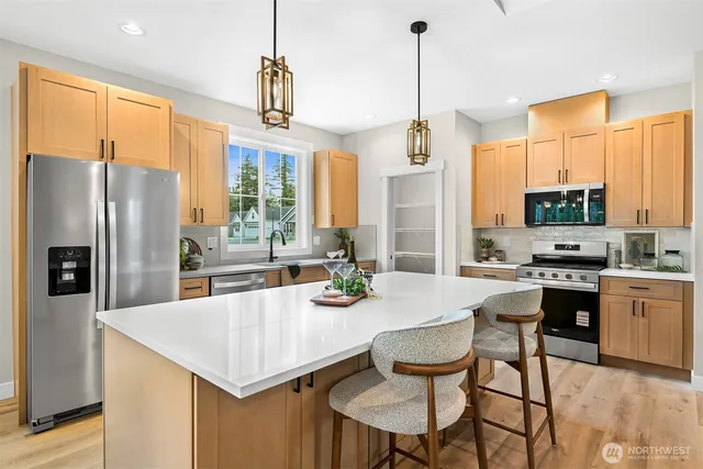 a kitchen with stainless steel appliances a dining table chairs and a refrigerator