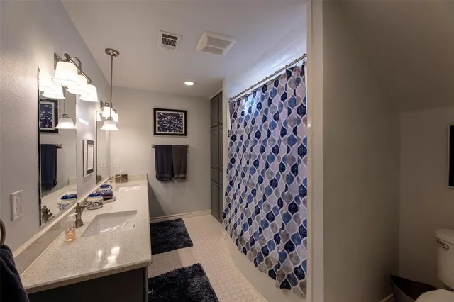 a bedroom with a bed a chandelier and dresser