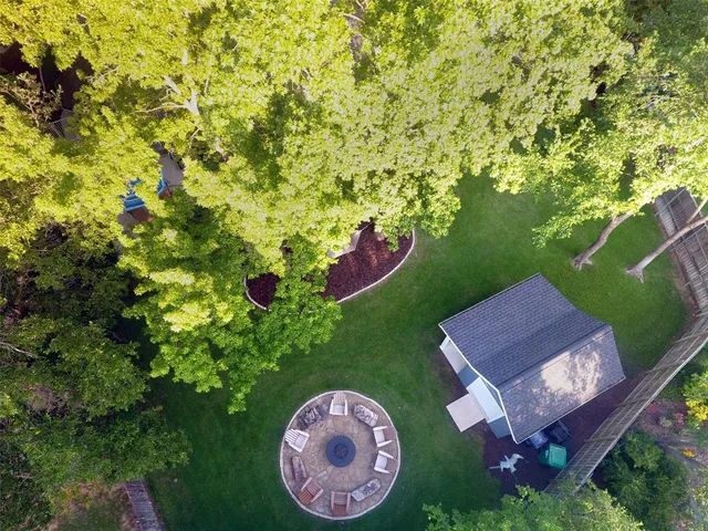 a view of a backyard with table and chairs potted plants and large tree
