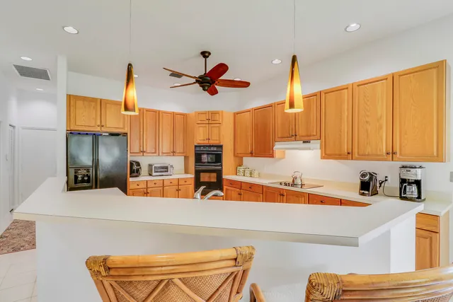 a kitchen with stainless steel appliances kitchen island granite countertop a sink and a refrigerator