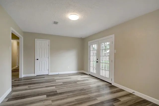 a view of an empty room with wooden floor and a window