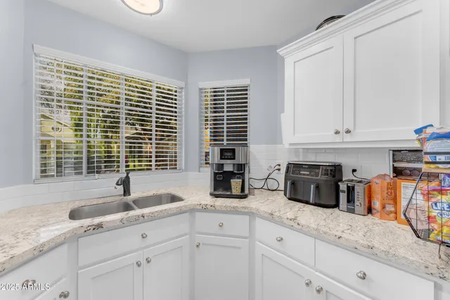 a kitchen with stainless steel appliances granite countertop white cabinets a window and a sink
