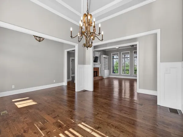 a view of an empty room with wooden floor fireplace and a window