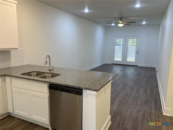 a kitchen with stainless steel appliances granite countertop a sink dishwasher a stove and white countertops with wooden floor