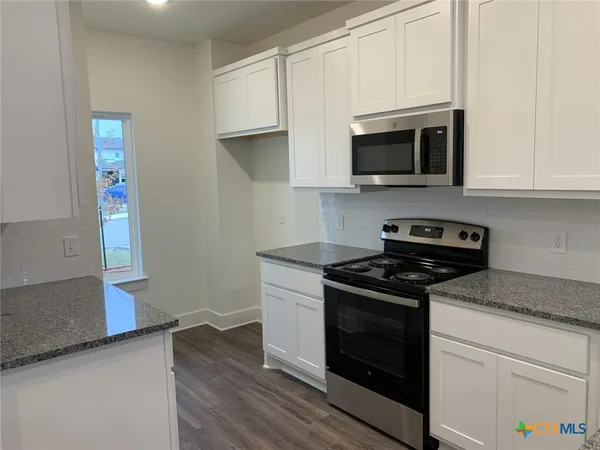 a kitchen with stainless steel appliances white cabinets and a stove top oven