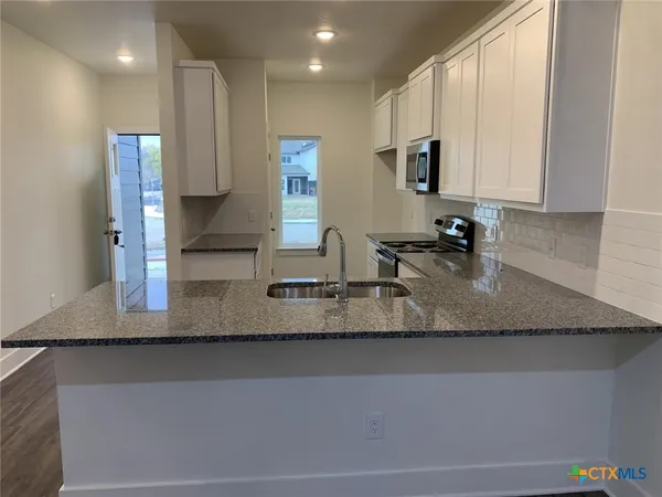 a view of a kitchen with kitchen island a sink stainless steel appliances and cabinets