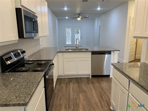 a kitchen with stainless steel appliances granite countertop a stove a sink and a microwave