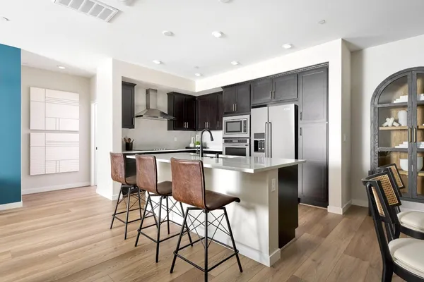 a kitchen with stainless steel appliances granite countertop a refrigerator a stove and a dining table with wooden floor