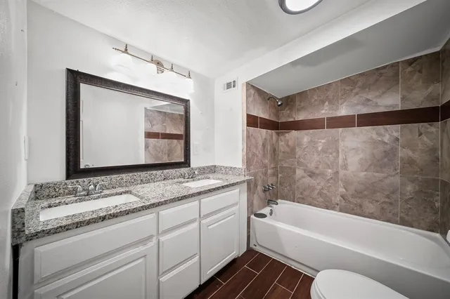 a bathroom with a granite countertop sink mirror vanity and bathtub