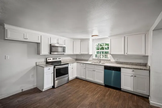 a kitchen with granite countertop white cabinets and white appliances