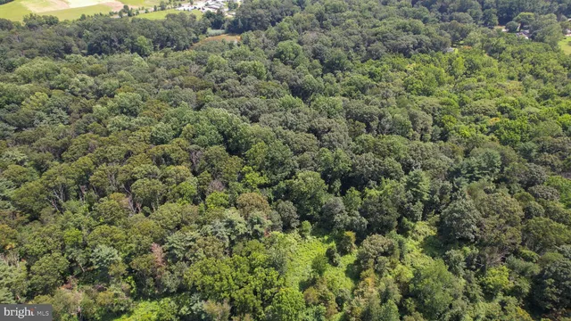 an aerial view of residential house with outdoor space and trees all around