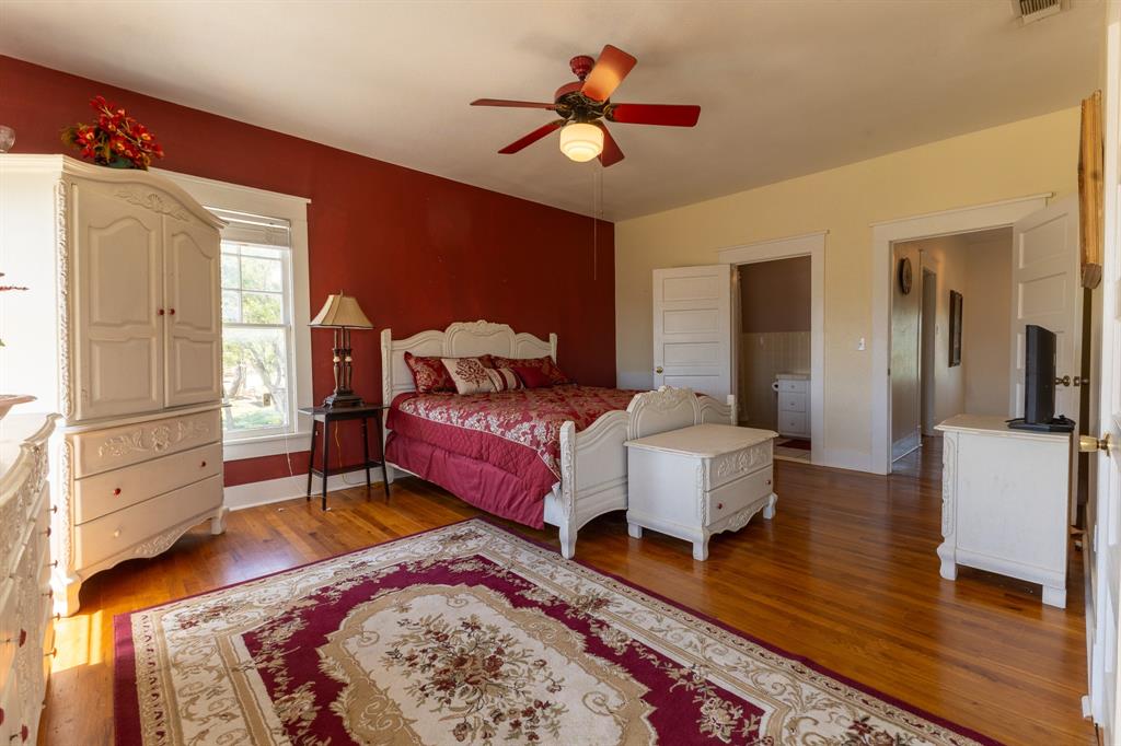1115 Austin Street Coleman, TX 76834 - Photo 21 of 40 a spacious bedroom with a bed and a chandelier