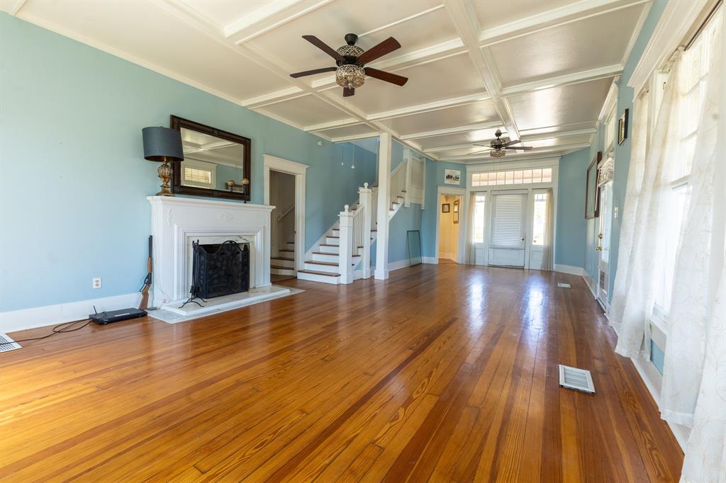 1115 Austin Street Coleman, TX 76834 - Photo 5 of 40 a view of a livingroom with wooden floor a ceiling fan and a kitchen
