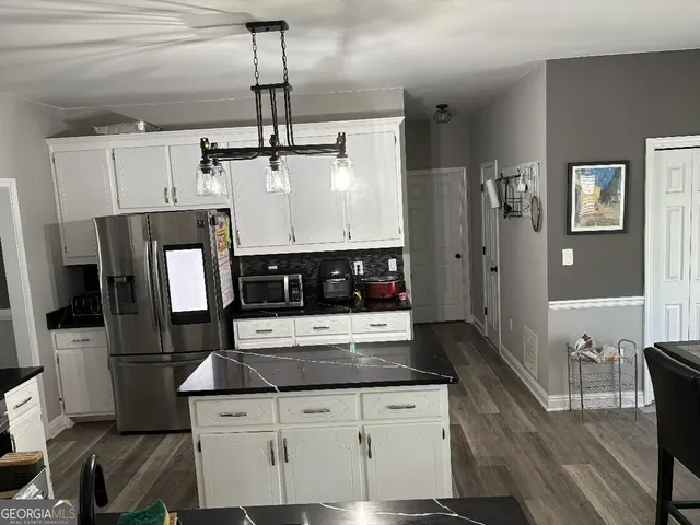 a kitchen with stainless steel appliances granite countertop a refrigerator a stove a sink dishwasher and white cabinets with wooden floor