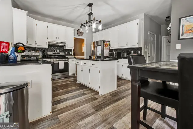 a kitchen with granite countertop a sink appliances cabinets and furniture