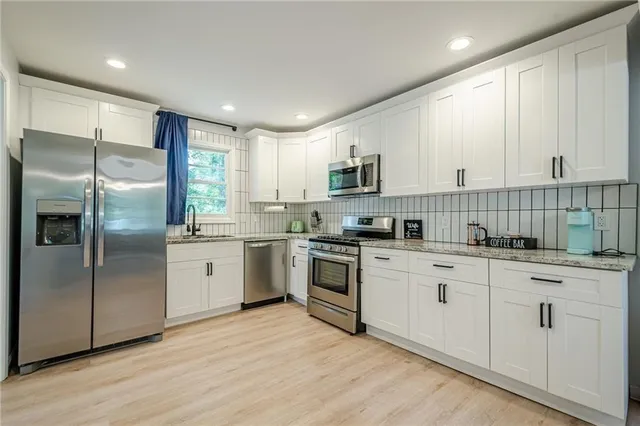 a kitchen with cabinets stainless steel appliances a sink and a window