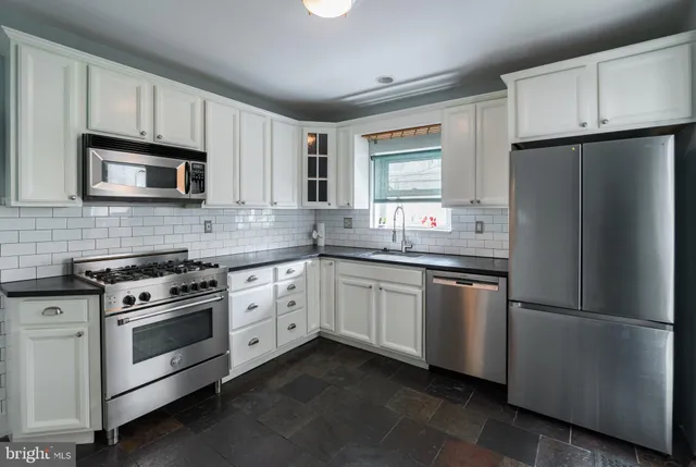 a kitchen with stainless steel appliances granite countertop a refrigerator stove a sink and a microwave