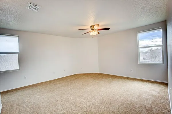 an empty room with windows and fan