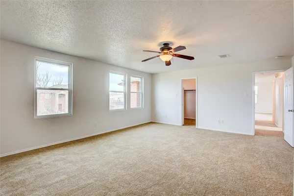 an empty room with windows and chandelier fan