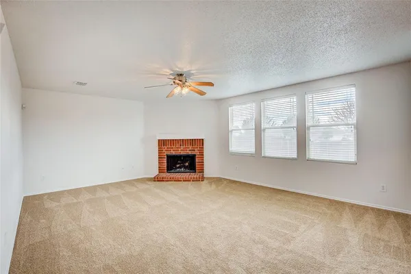 an empty room with windows and fireplace