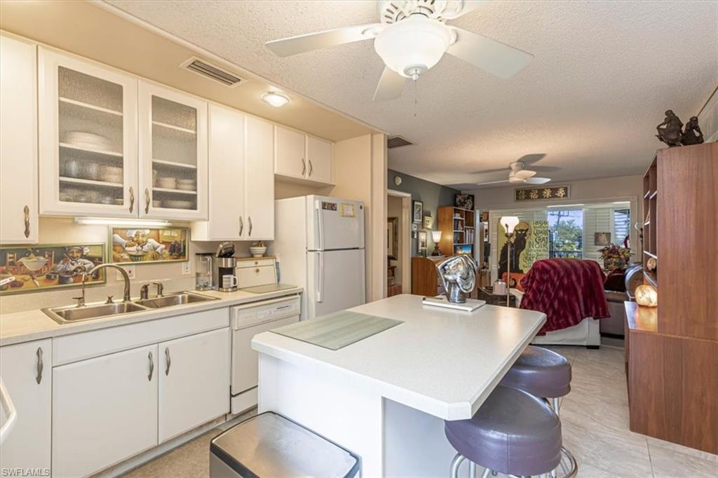 5 High Point Circle West, Unit 308 Naples, FL 34103 - Photo 11 of 28 a kitchen with a sink a refrigerator and cabinets