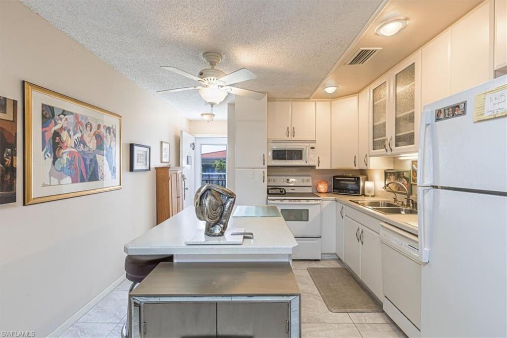 5 High Point Circle West, Unit 308 Naples, FL 34103 - Photo 13 of 28 a kitchen with stainless steel appliances a refrigerator a stove a sink and white cabinets with wooden floor