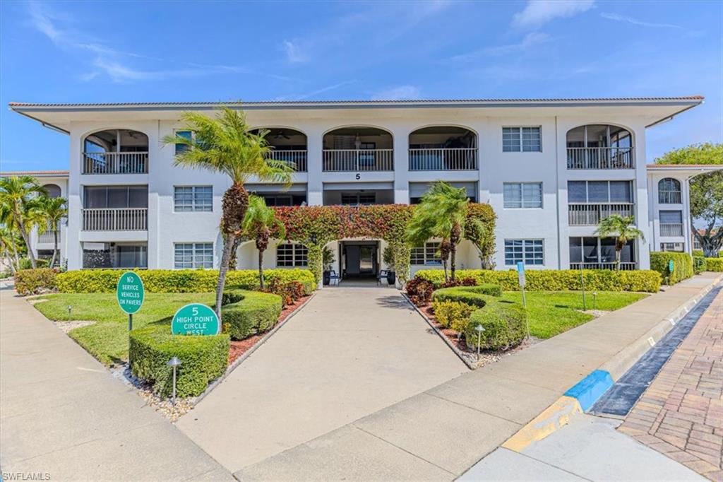 5 High Point Circle West, Unit 308 Naples, FL 34103 - Photo 2 of 28 a front view of a house with outdoor seating and flower plants