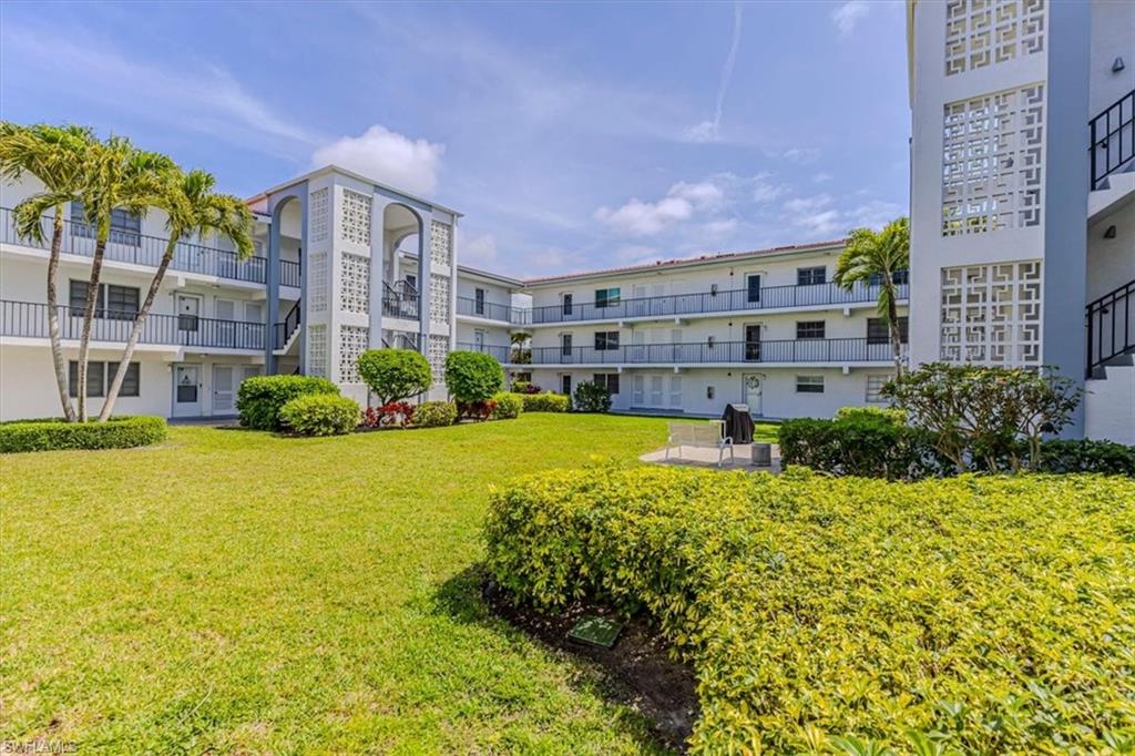 5 High Point Circle West, Unit 308 Naples, FL 34103 - Photo 22 of 28 a large building with a swimming pool in front of it