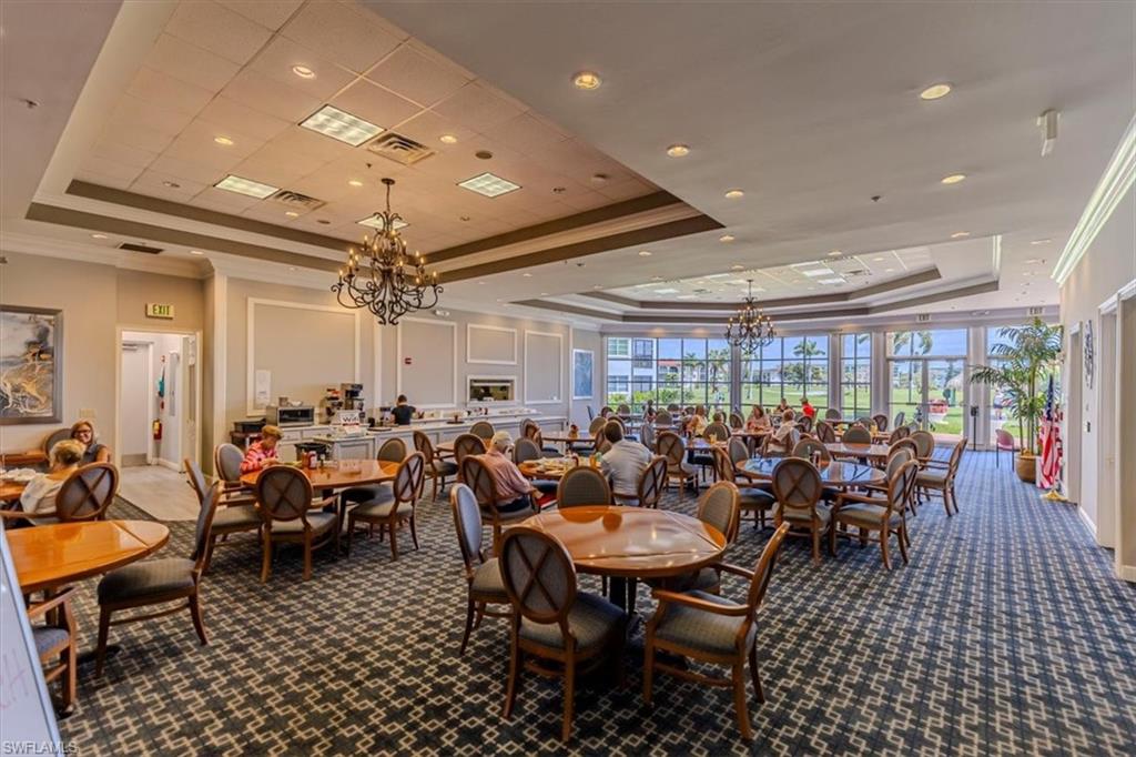5 High Point Circle West, Unit 308 Naples, FL 34103 - Photo 23 of 28 a room with lots of chairs a chandelier and a projector screen