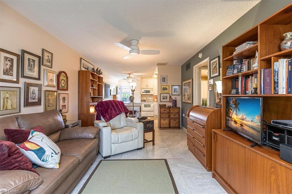 5 High Point Circle West, Unit 308 Naples, FL 34103 - Photo 5 of 28 a living room with furniture a bookshelf and a book shelf