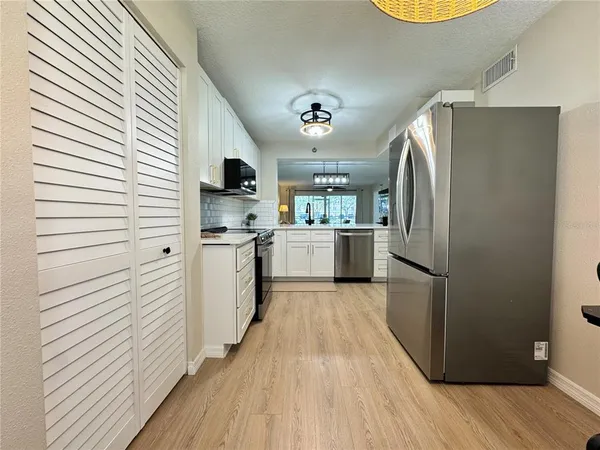 a kitchen with stainless steel appliances a refrigerator sink and white cabinets