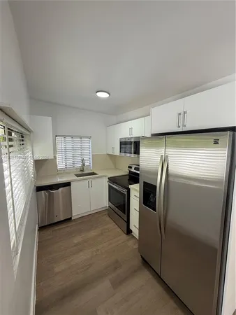 a kitchen with stainless steel appliances a refrigerator a sink a stove a microwave a center island and cabinets