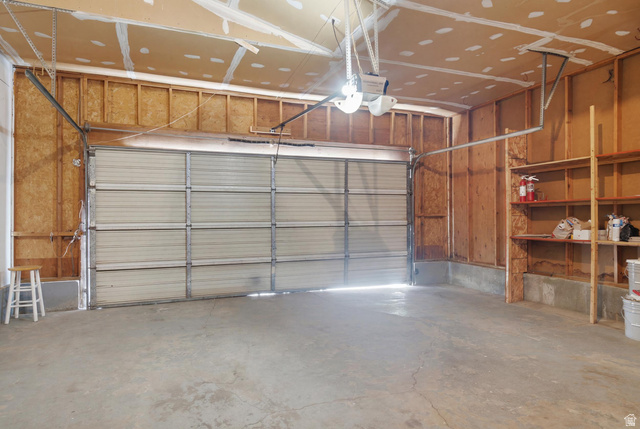 7910 Woolley Way Magna, UT 84044 - Photo 20 of 26 Attached two-car garage featuring a concrete floor, built-in shelving, and exposed wood framing