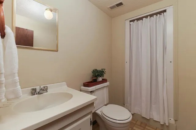 a bathroom with a sink a toilet a mirror and shower curtain