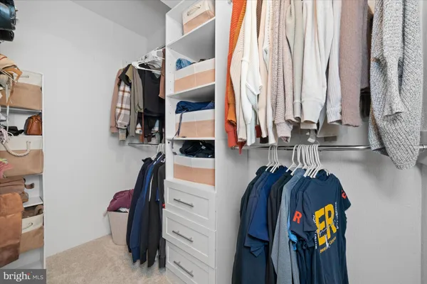 a view of walk in closet with clothes and shoes