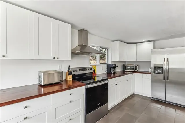 a kitchen with stainless steel appliances granite countertop a refrigerator sink and white cabinets