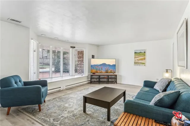 a living room with furniture and a flat screen tv with wooden floor