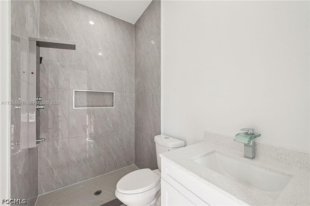 4402 East 19th Street Lehigh Acres, FL 33972 - Photo 15 of 27 a bathroom with a granite countertop sink a toilet and shower