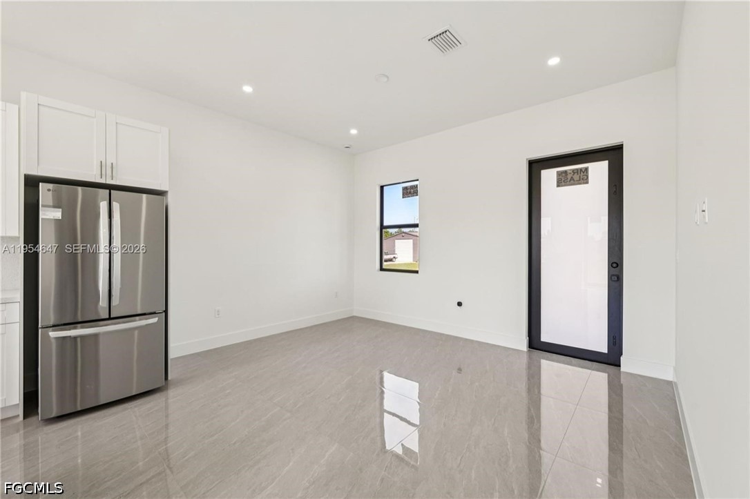 4402 East 19th Street Lehigh Acres, FL 33972 - Photo 4 of 27 a view of an empty room with wooden floor and a kitchen