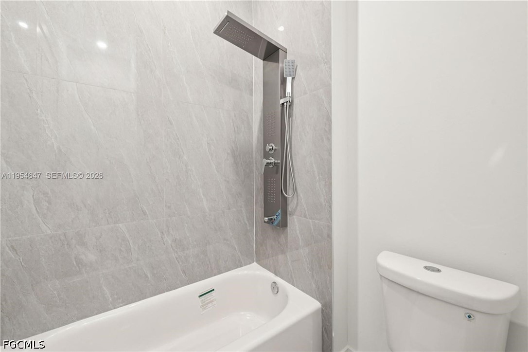 4402 East 19th Street Lehigh Acres, FL 33972 - Photo 10 of 27 a bathroom with a white bath tub and a toilet