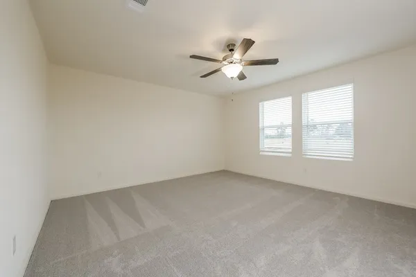 an empty room with windows and fan