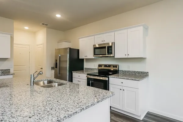 a kitchen with stainless steel appliances granite countertop a sink stove and refrigerator