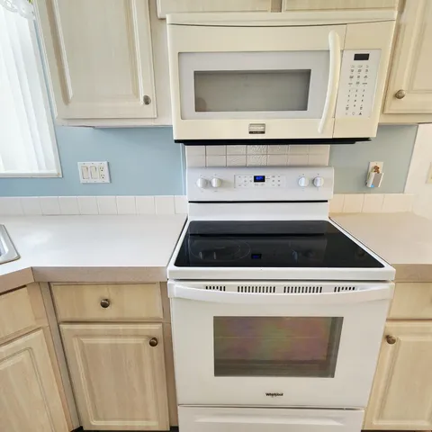 a dining hall with granite countertop white cabinets and wooden floor