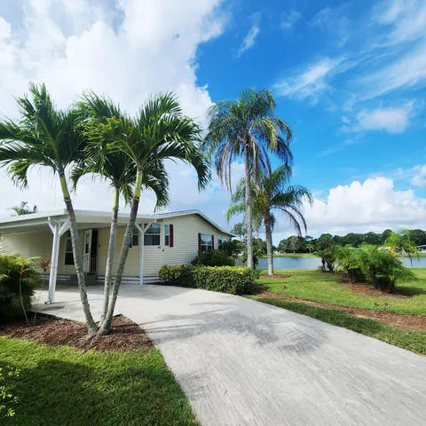 a front view of a house with garden and trees