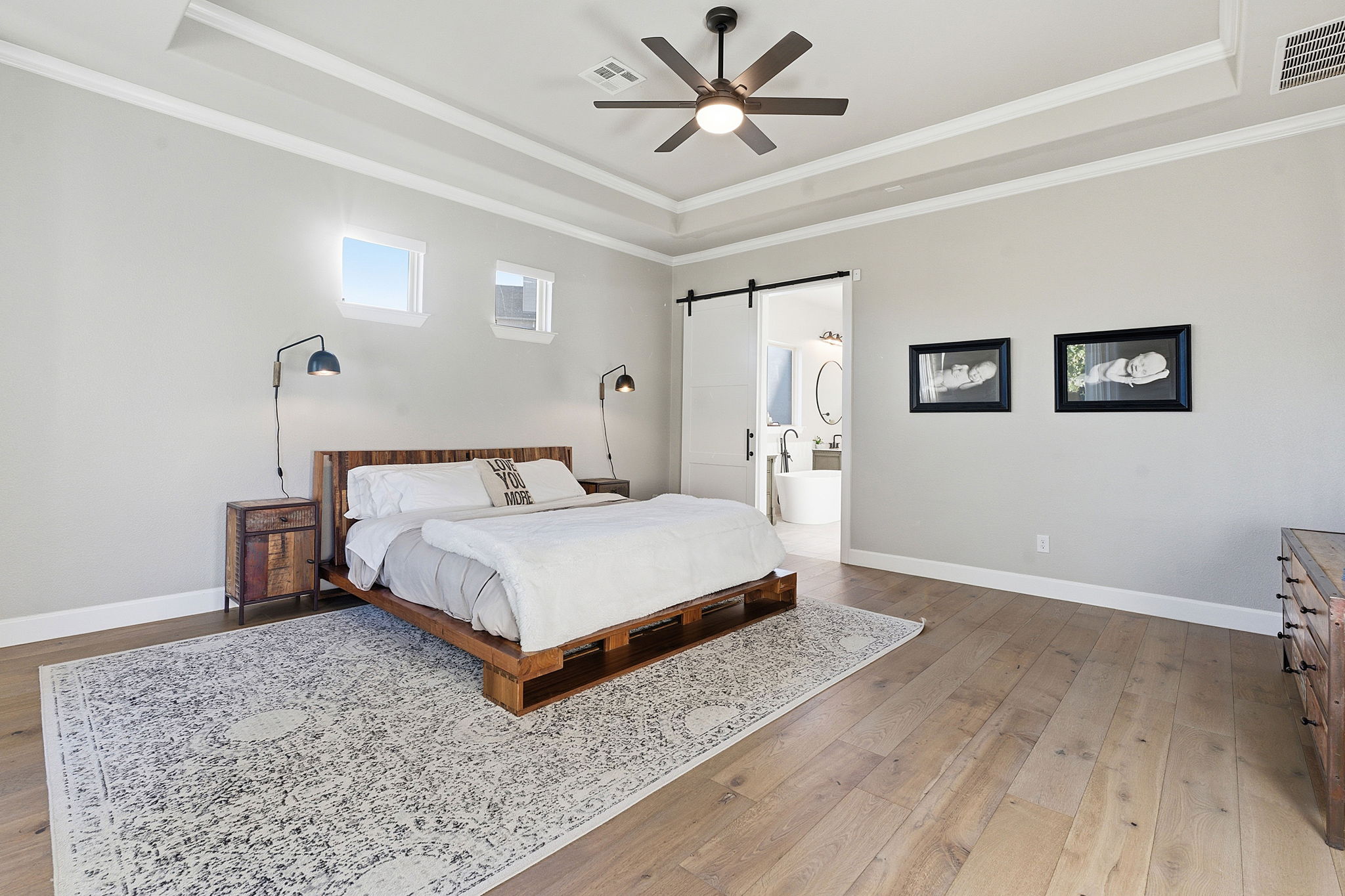 512 Choke Canyon Lane Georgetown, TX 78628 - Photo 13 of 37 Bedroom featuring a barn door, ornamental molding, light wood-type flooring, ceiling fan, and a tray ceiling